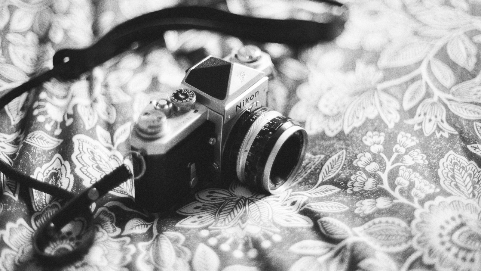 Appareil photo argentique Nikon F posé sur une nappe fleurie