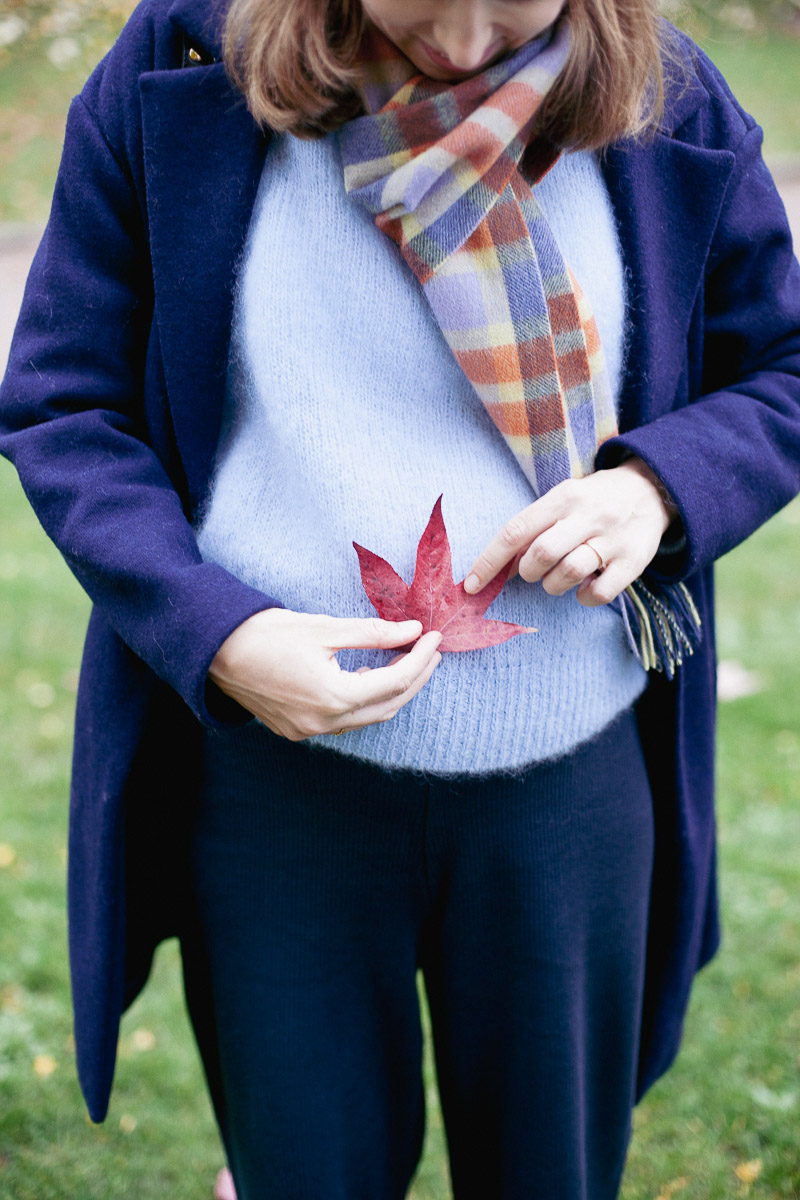 Mathilde pose une feuille rouge sur son ventre arrondi.