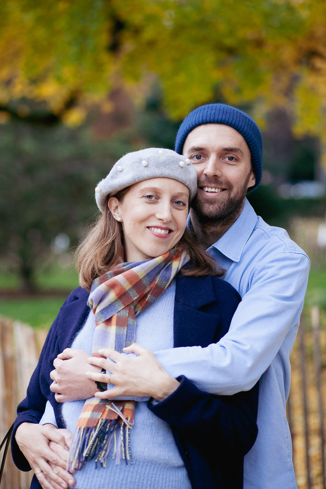 Portrait de Mathilde et Tanguy qui s'enlacent face à l'objectif devant un arrière plan jaune automnal.